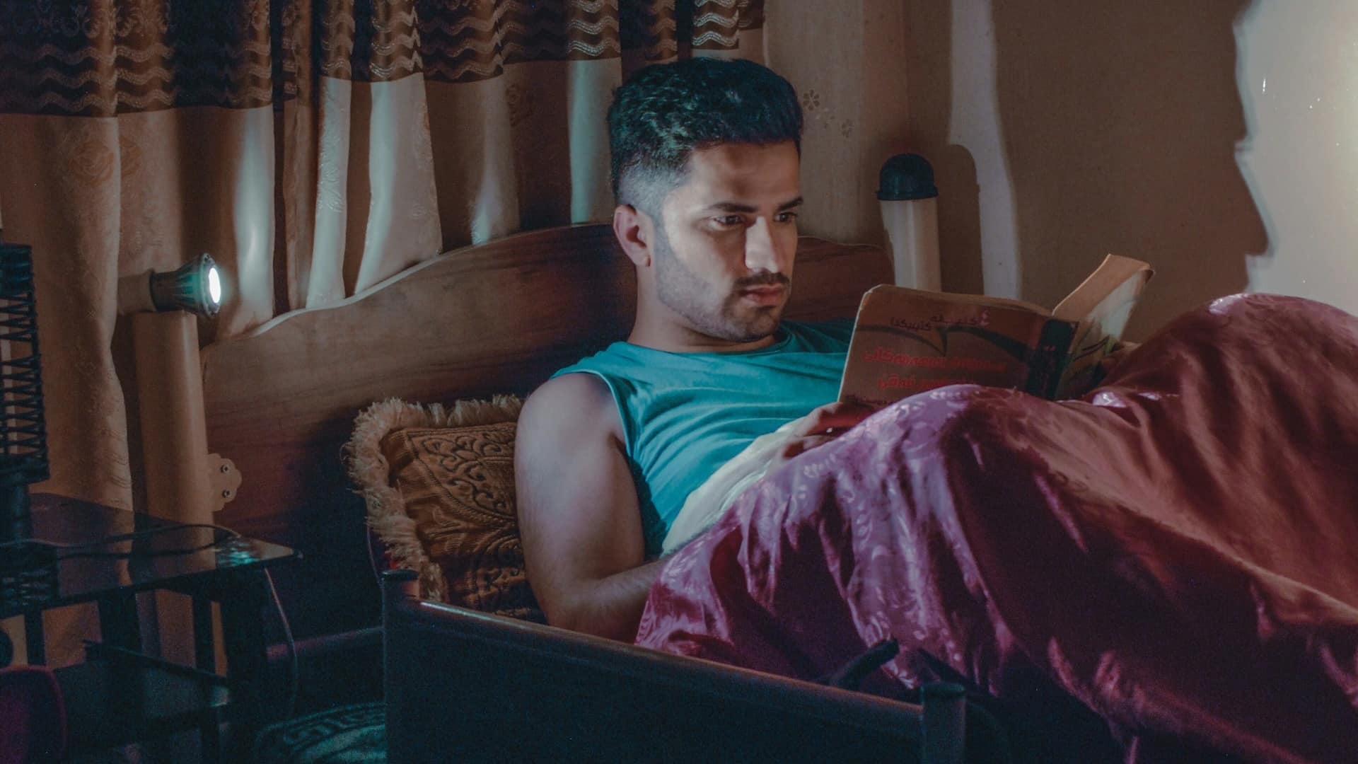 A man sitting in bed and reading a book