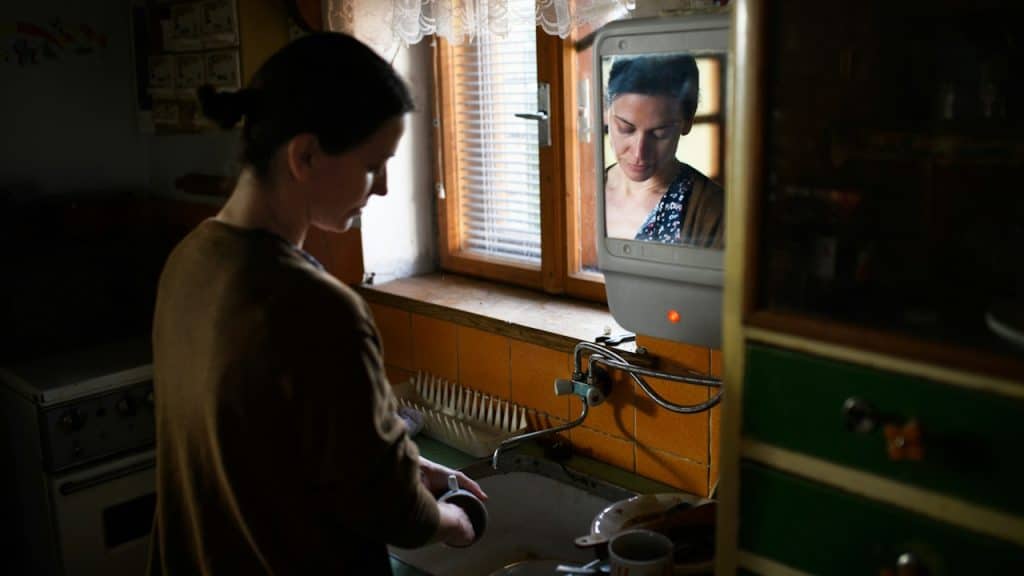 A poor, mature woman washing dishes indoors at home.