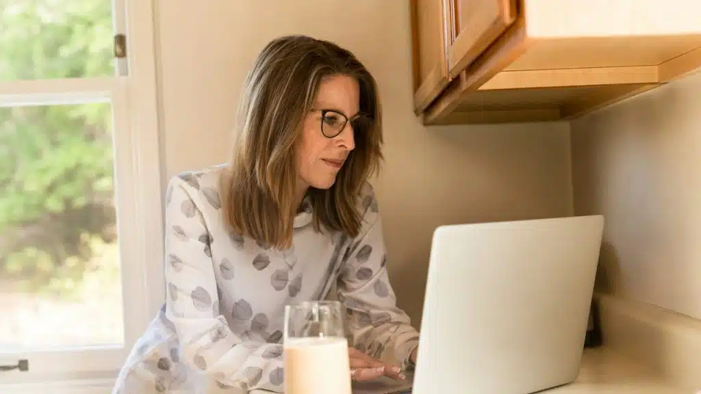 A woman using her MacBook Pro inside a white room.