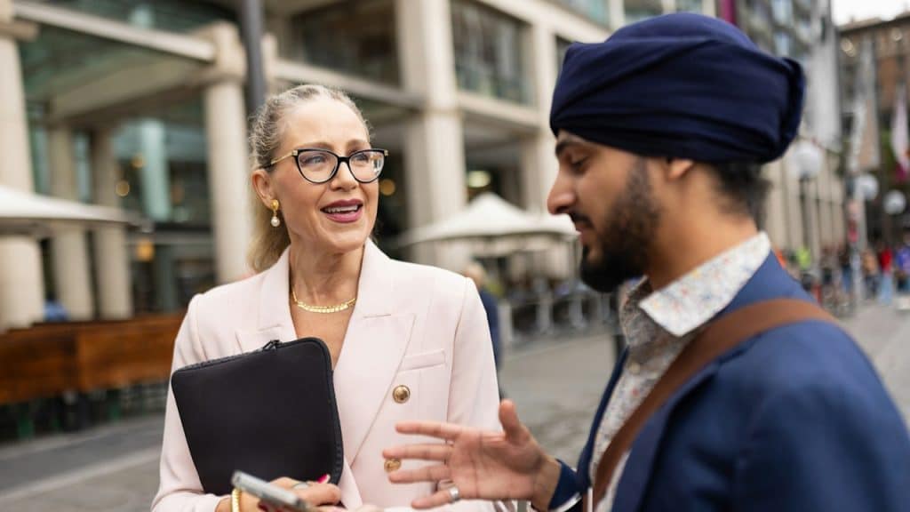 A man and a woman are busy in conversation outside an office.