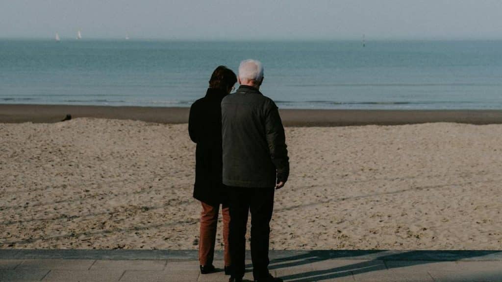 A couple is standing on the beach beside the sea.