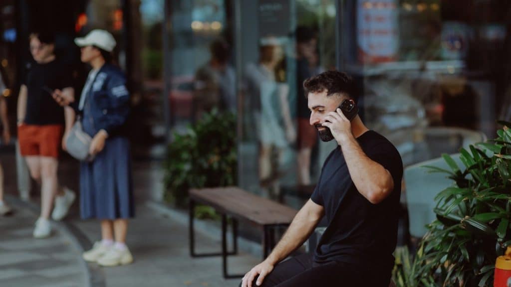 A man talking on the phone while sitting on a bench.
