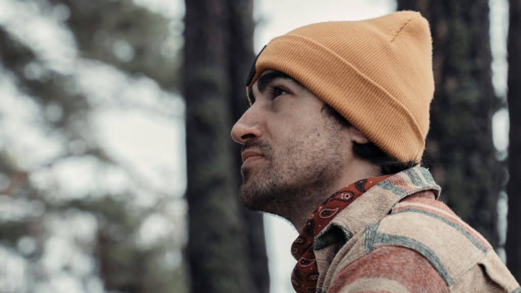 A man looking upward while sitting in woods.