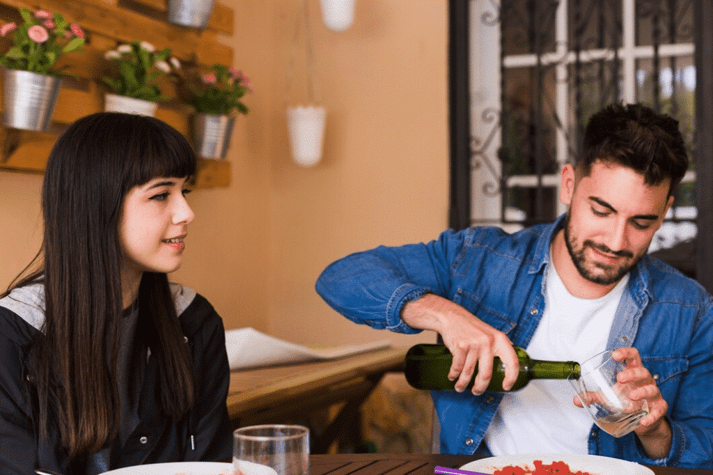 Young woman looking at a man pouring alcohol in glass