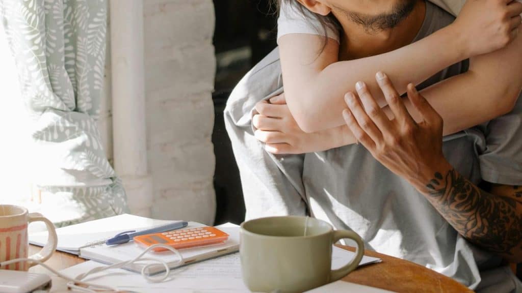 A man holding a child while sitting at a table with papers and a calculator.