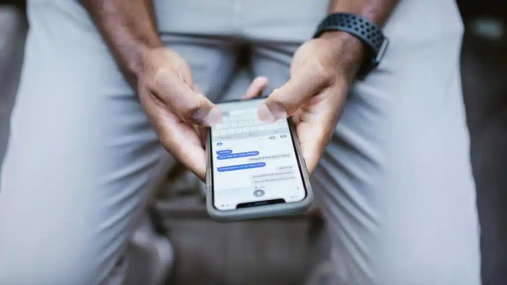 A person holding a smartphone and typing a text message.
