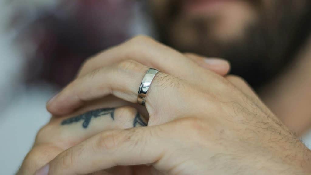 Close-up of a person's hands clasped together, showing a silver band on one finger.
