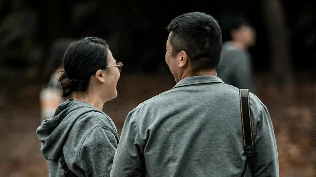 A couple standing with their backs to the camera and smiling at each other.