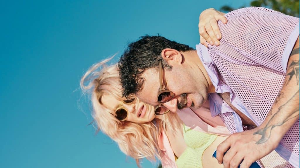 A man and a woman on a beach with trees in the background.