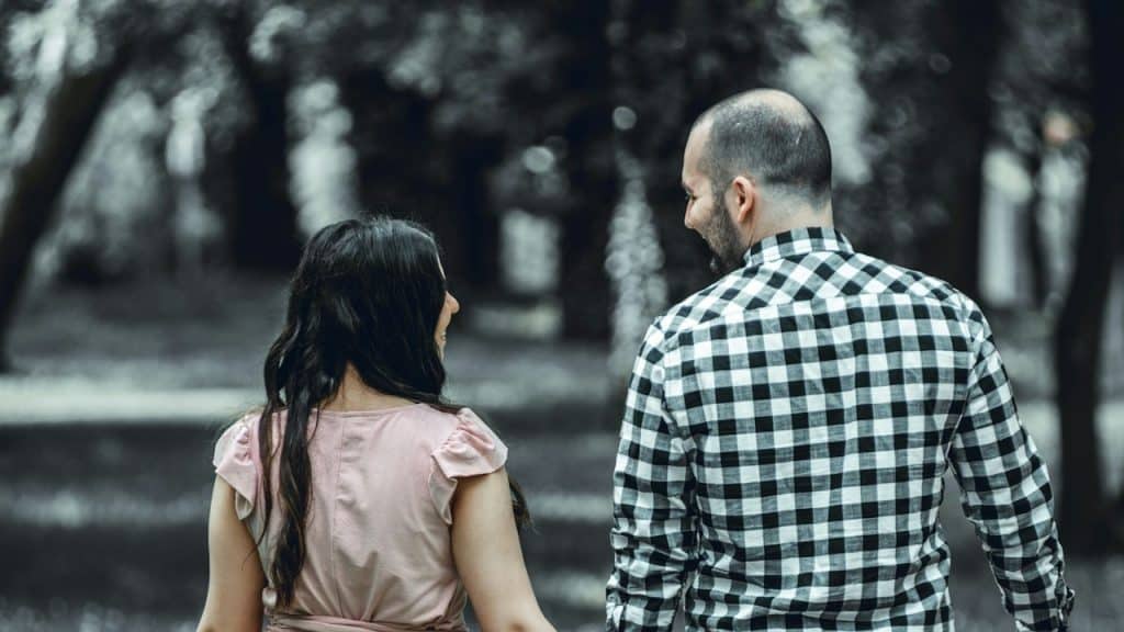 A couple smiling at each other and walking down a path.