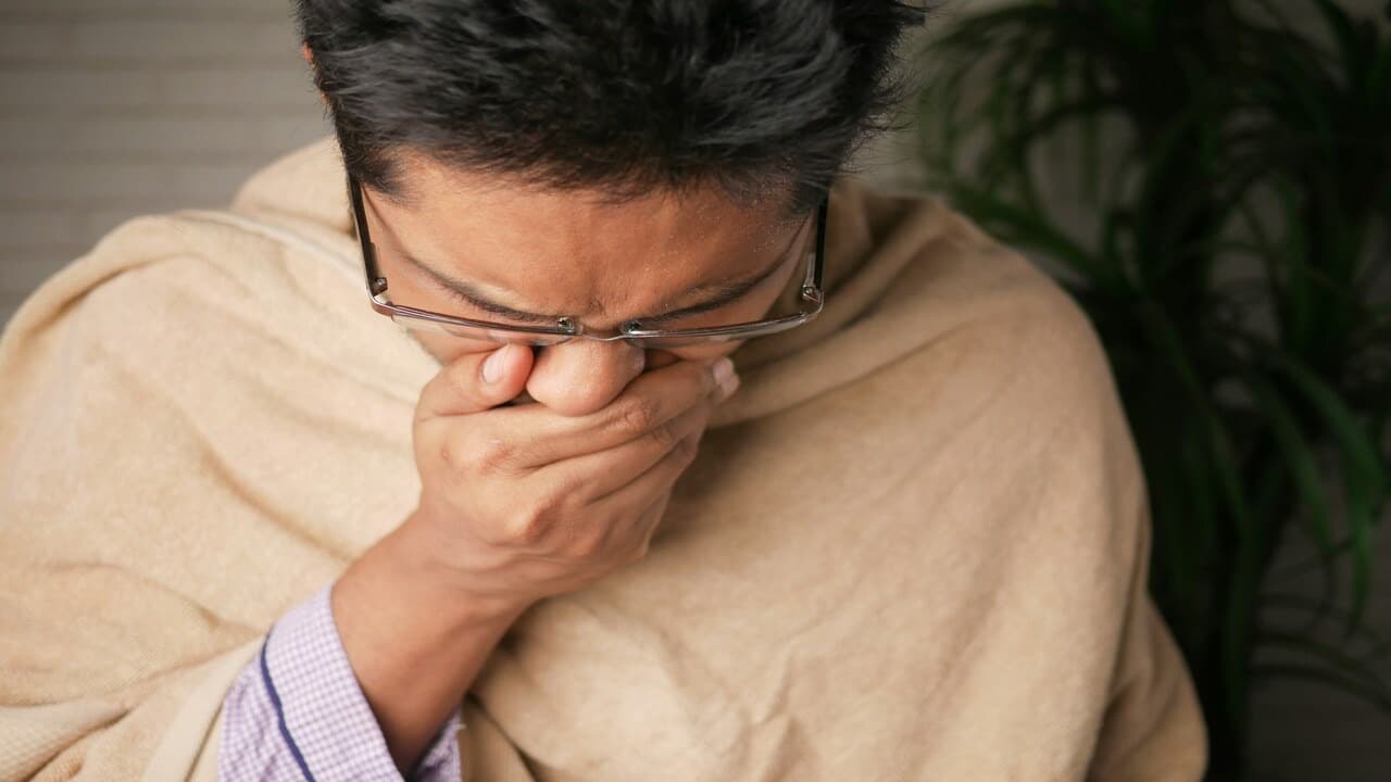 A man sneezing at home