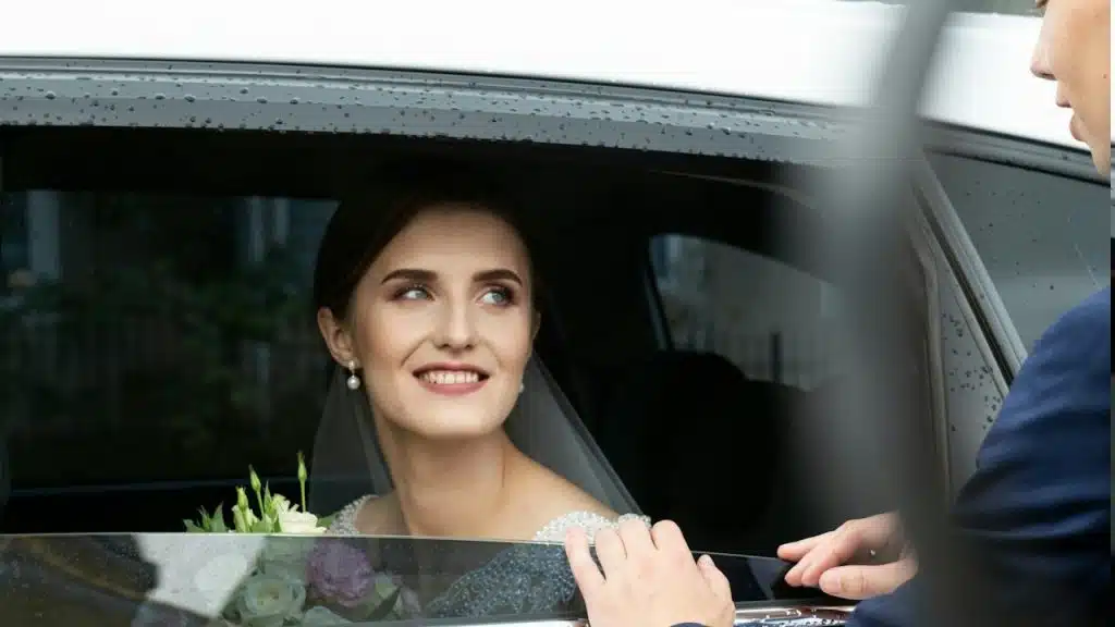 A woman sitting in a car with a bouquet of flowers.