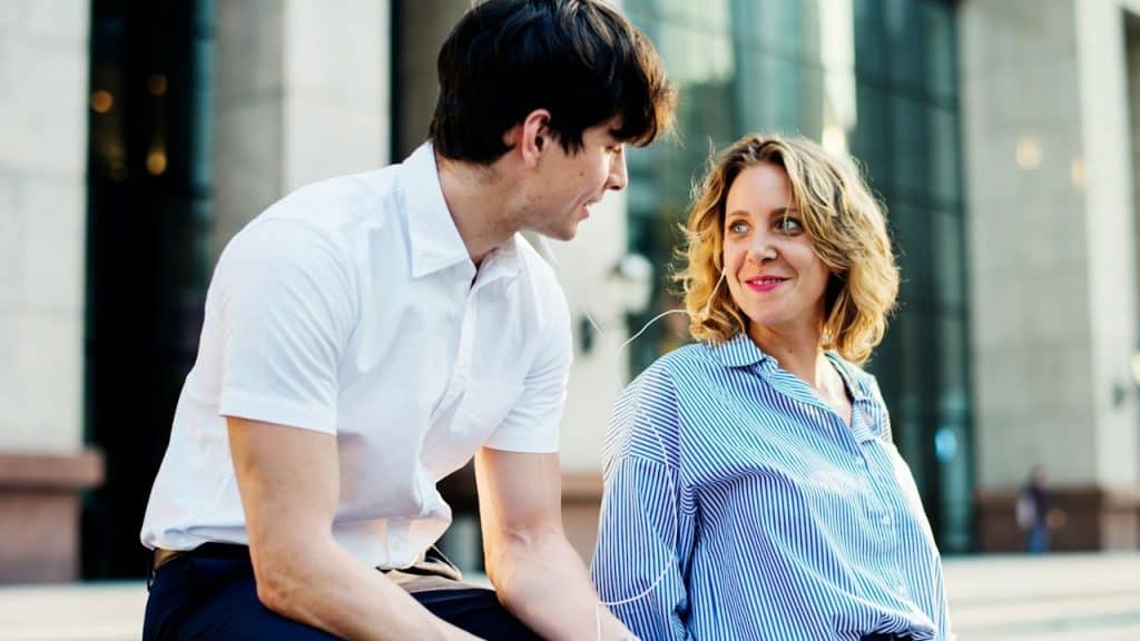 A man and a woman listening to a song together from a common hands-free.
