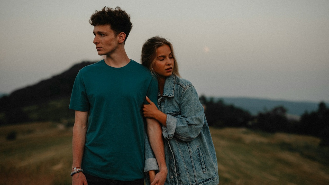 A couple standing close to each other but looking away.