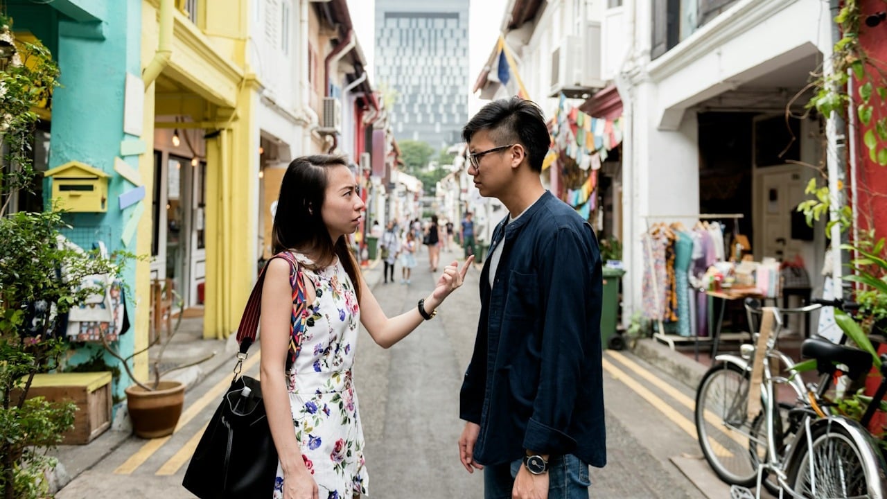 A woman pointing her finger at a man while they are standing on a street.