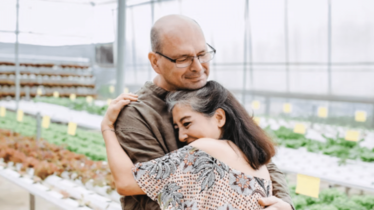 A mature couple hugging in a green house