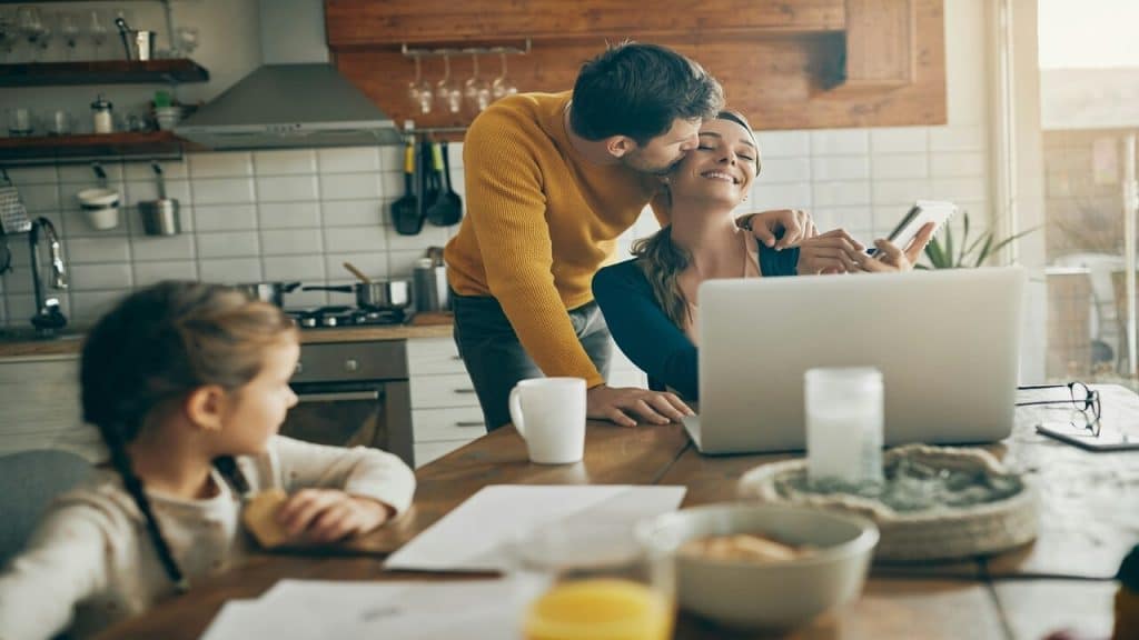 A man kissing his wife in the kitchen