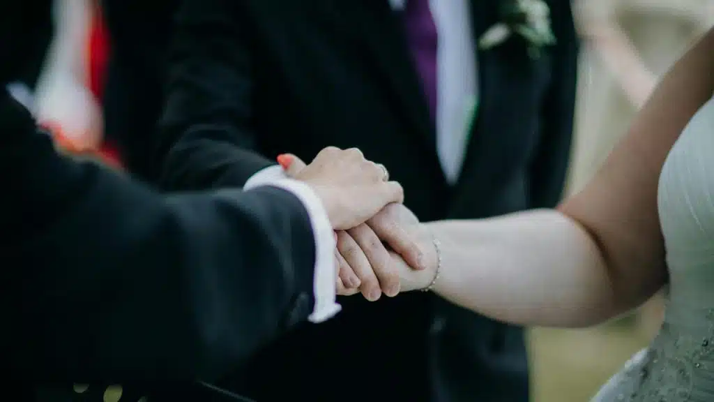 A couple holding hands during a wedding ceremony.