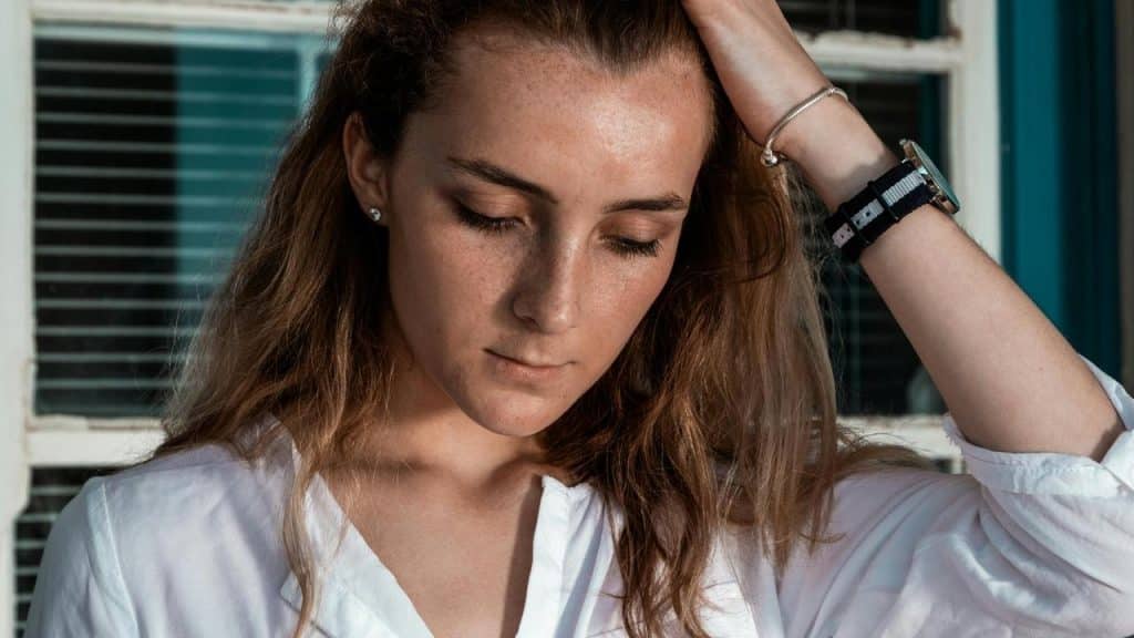 A woman looking down thoughtfully with her hand in her hair.