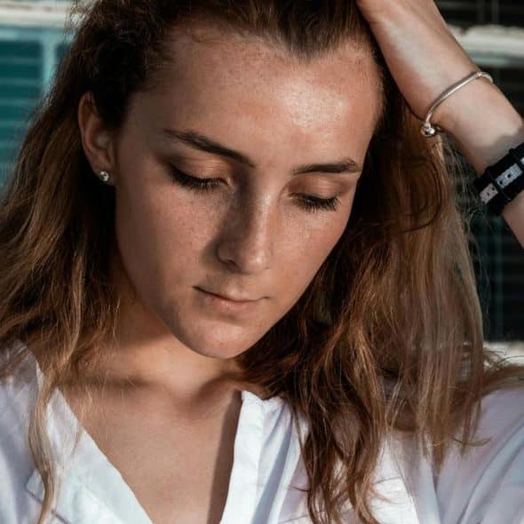 A woman looking down thoughtfully with her hand in her hair.