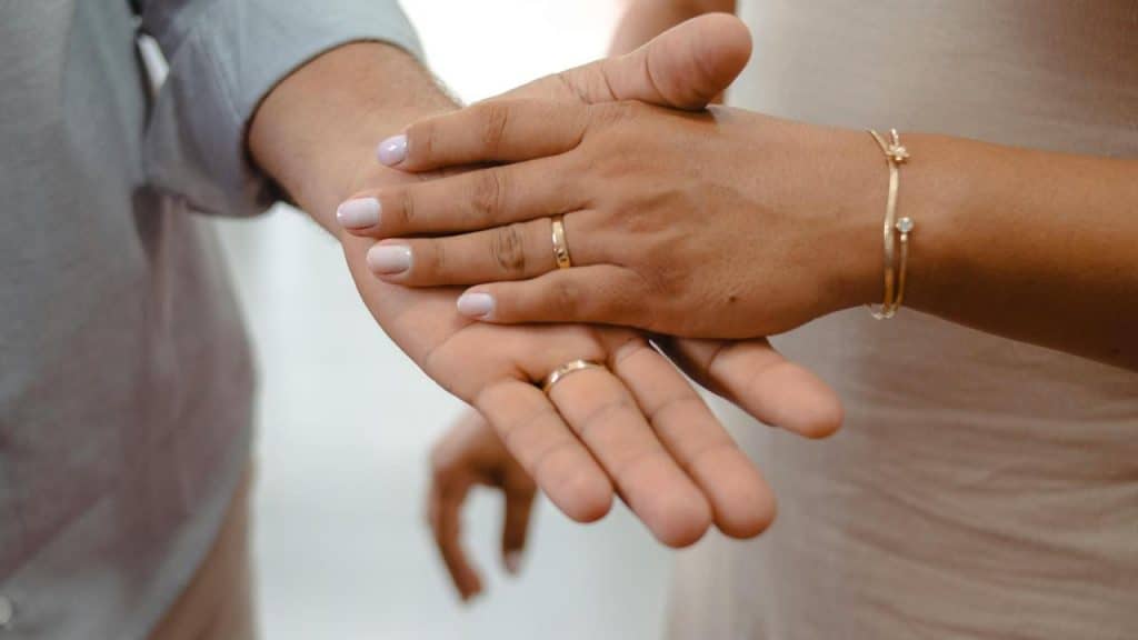 A couple showing their wedding rings while holding hands.