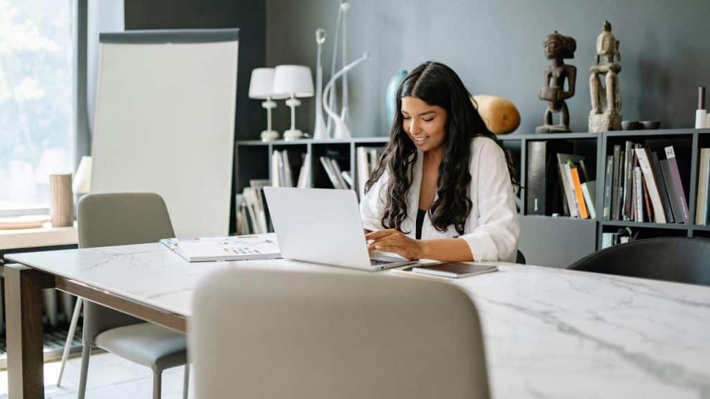 A woman working on a laptop at a modern office desk.