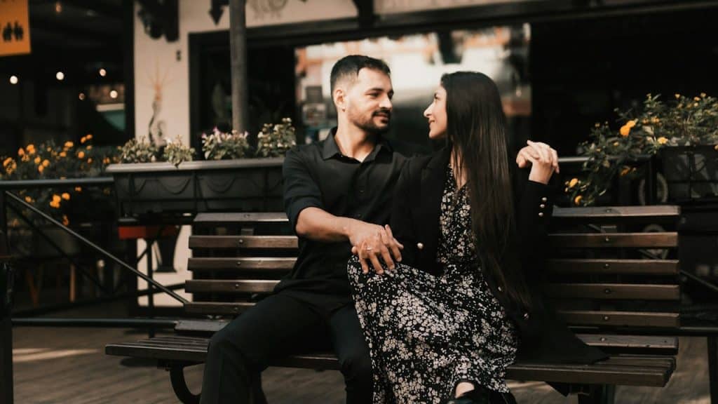 A couple sitting together on a bench.