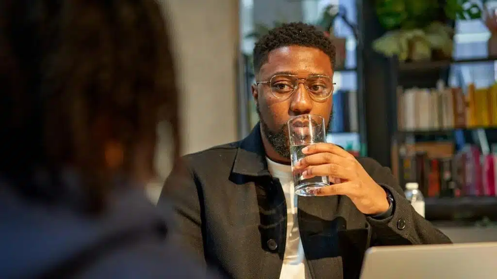 A man sitting at a table with a glass of water in front of him.
