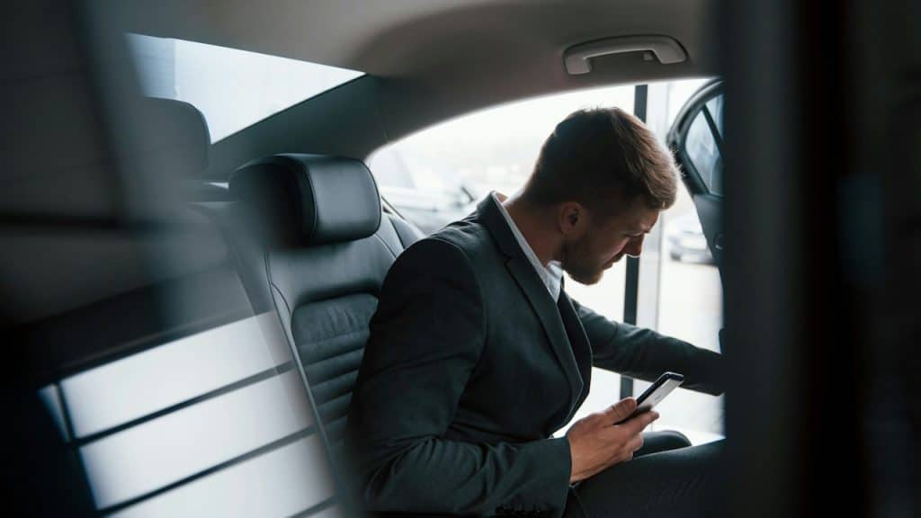 A businessman in official wear has a call when sitting in the back of a car.