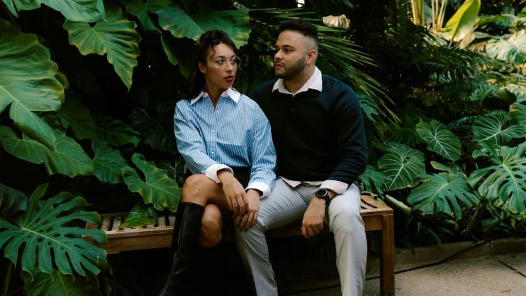 A couple sitting on a bench in a lush botanical garden.