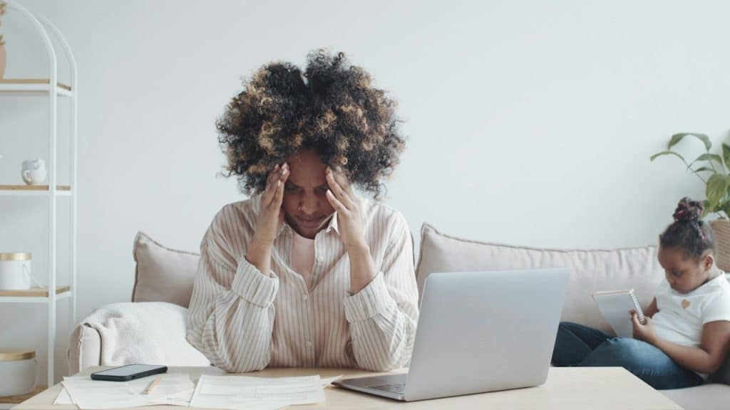 A young stressed African woman has no money to pay debts and rent for the apartment, holding her head in despair with a headache.