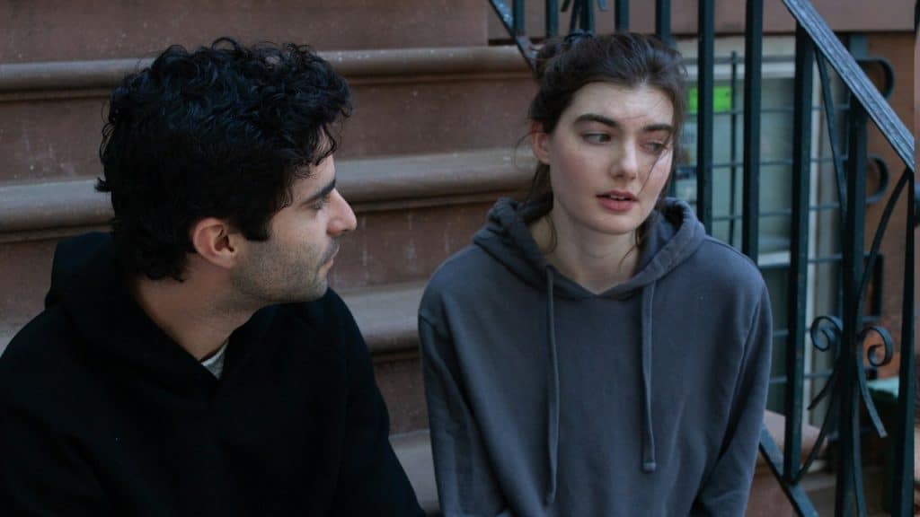 A man and a woman talking while sitting on stairs.