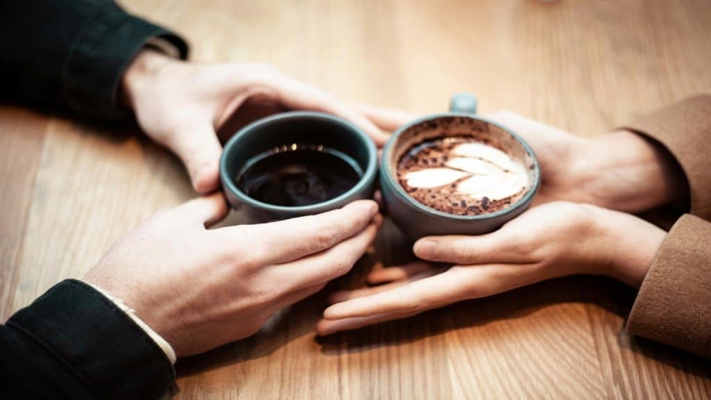 Two hands holding mugs of coffee