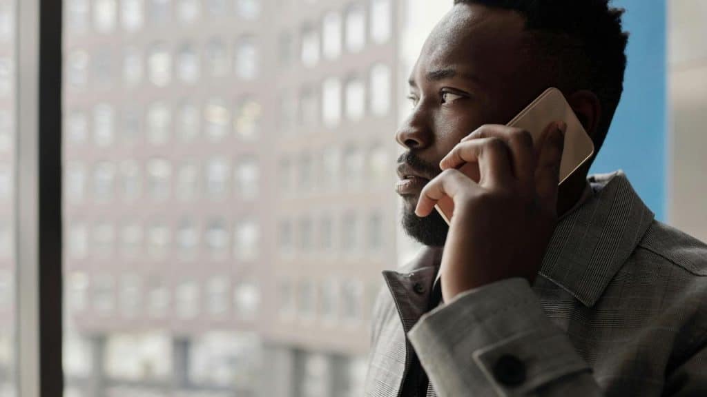 A man standing beside a window on the phone.