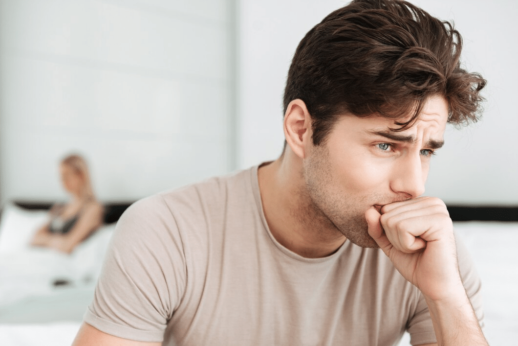 Sad man sitting in bed at home