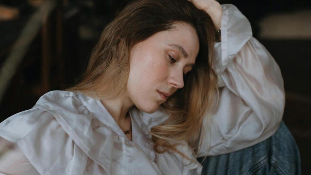 A woman resting her head on her hand with a thoughtful expression.