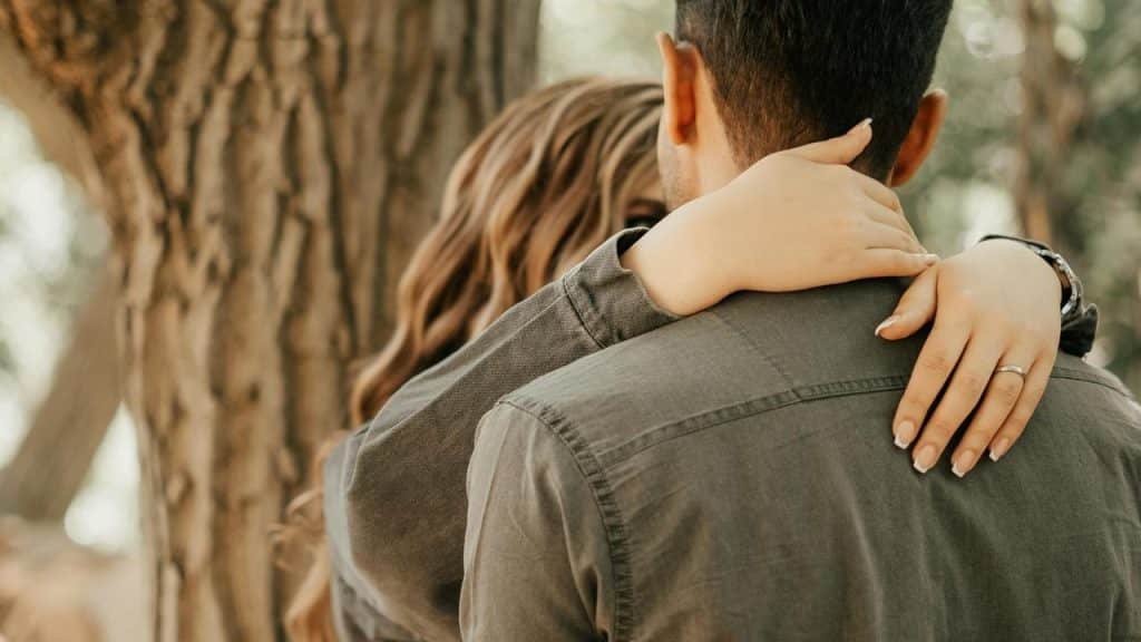 A couple embracing outdoors with arms around each other.