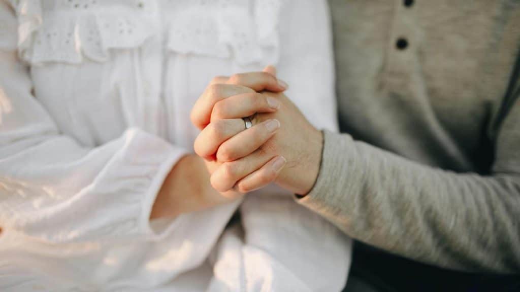 A couple holding hands closely together.