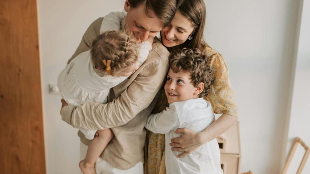 A family hugging closely together indoors.