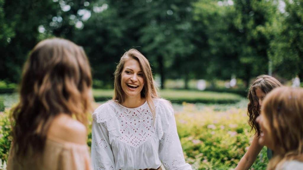 A woman laughing while talking with friends in a park.