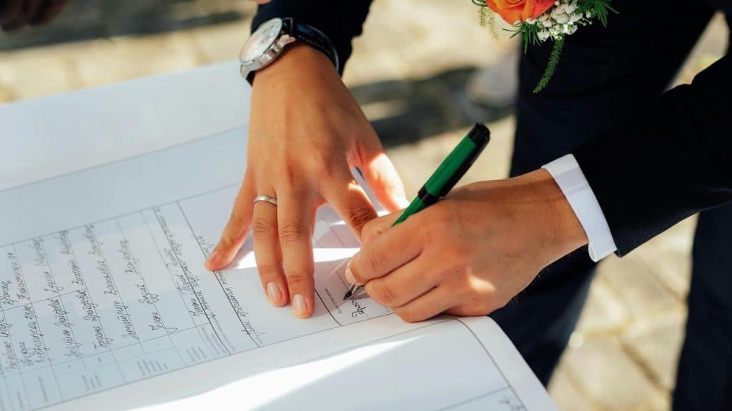 A person signing a document while wearing a ring.
