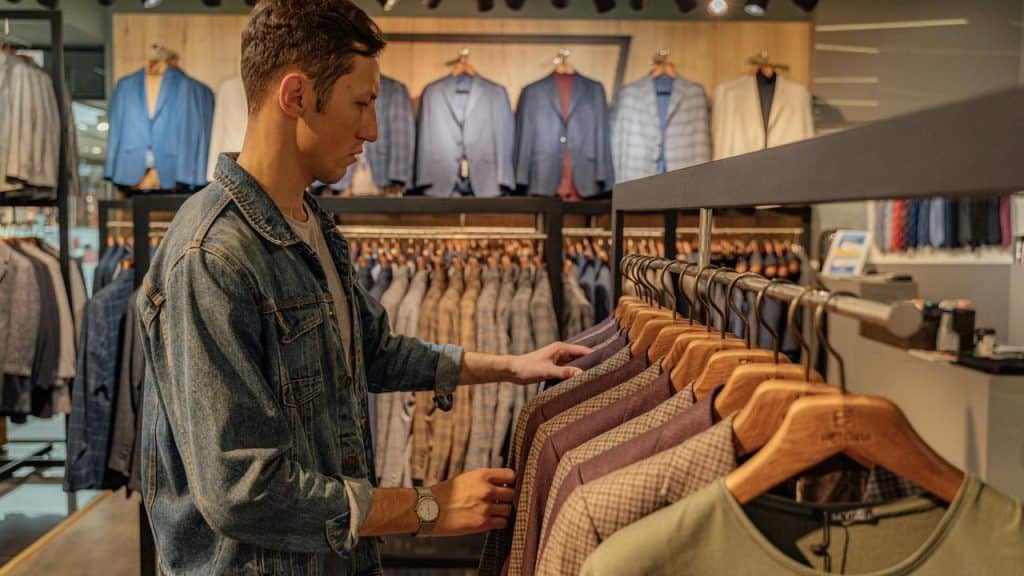 A man browsing jackets on a clothing rack in a store.