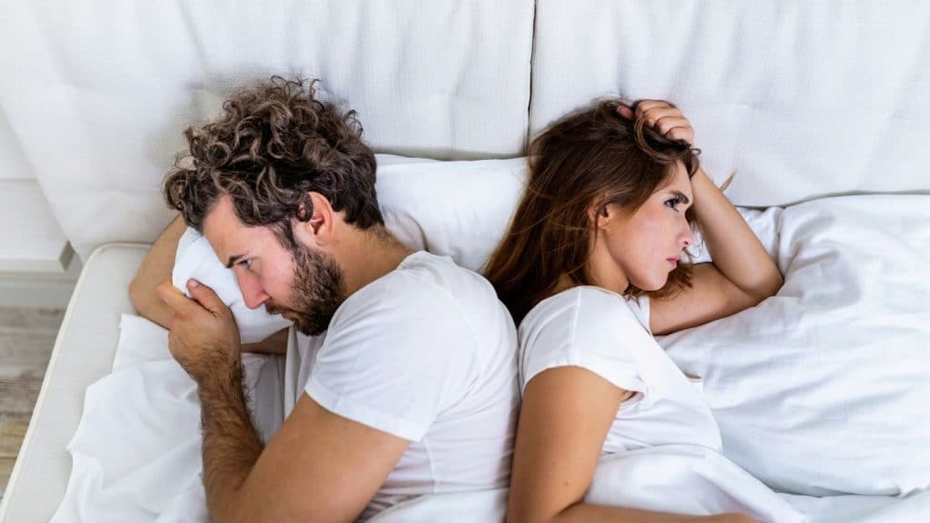 A man and woman at bed and having a thought