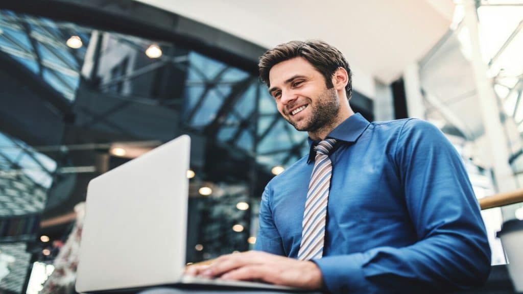 A man smiling at his laptop by himself