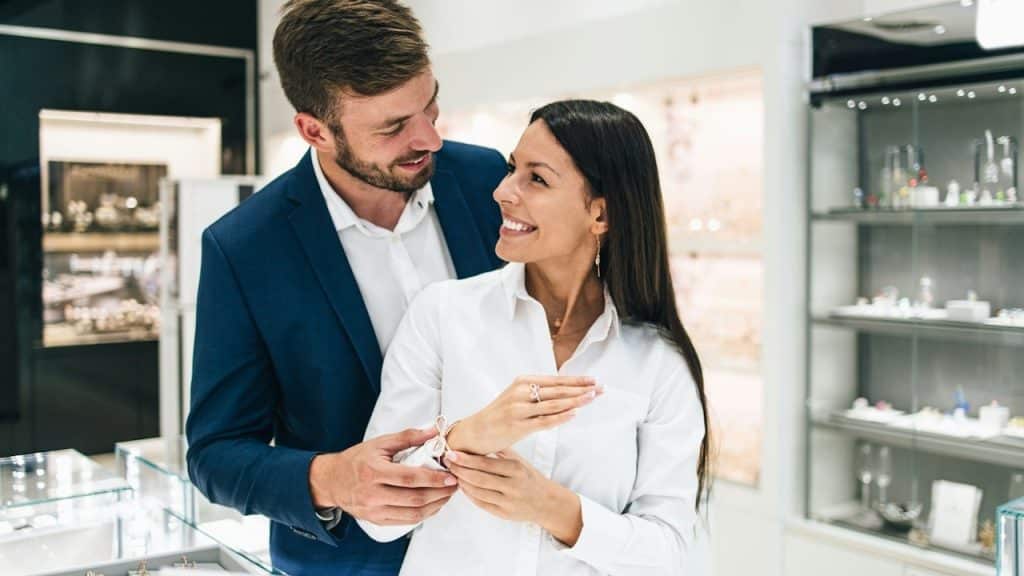 Beautiful couple enjoying in shopping at a modern jewelry store—close-up shot of woman's hand with gorgeous expensive ring and bracelet.