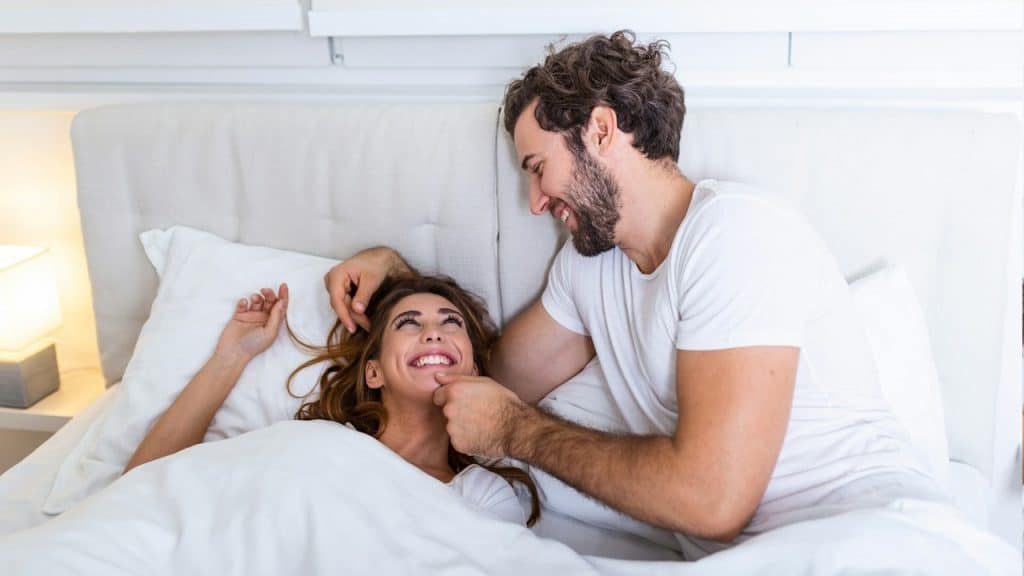 Young couple hugging and smiling while lying on the bed in a bedroom at home.