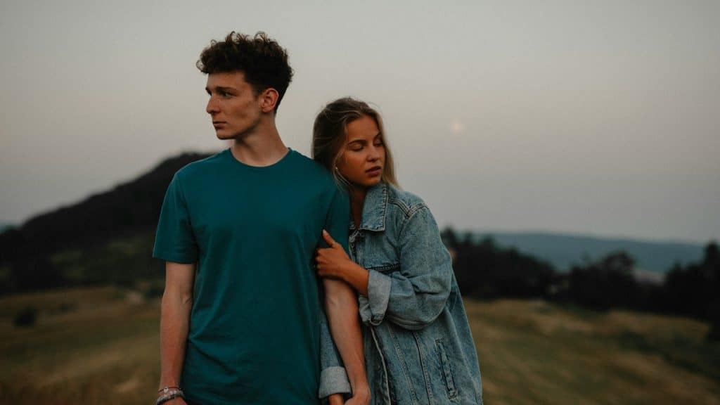 A couple standing with each other but looking away from each other.