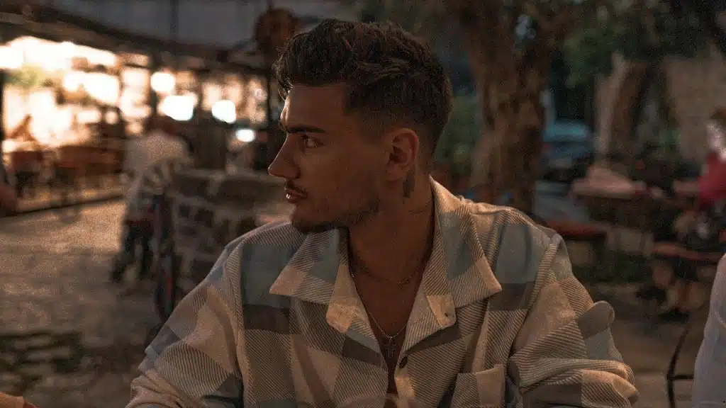 A side view of a man sitting alone and looking away.
