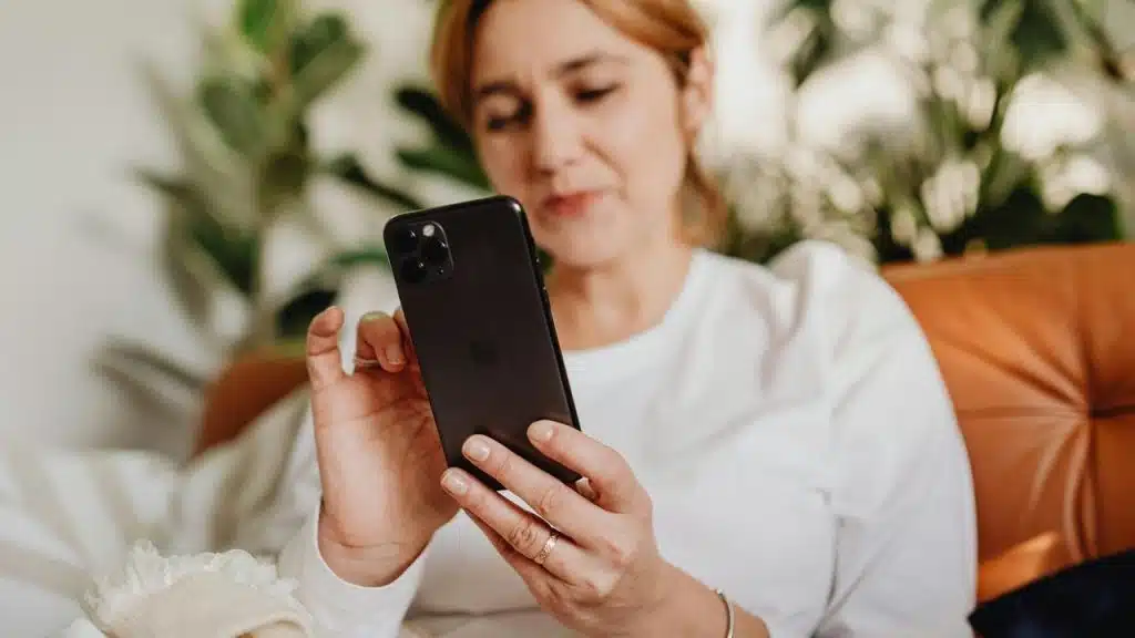 A woman looking at her smartphone while sitting on a couch.