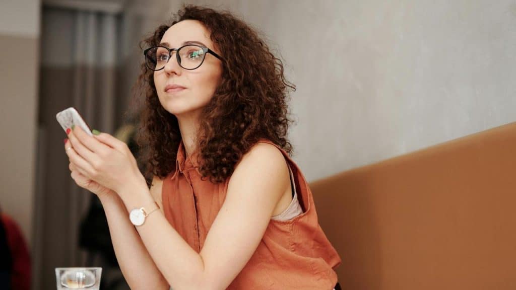 A person holding a smartphone while sitting at a table.